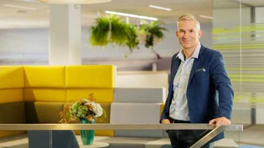 Decoratieve foto van een mannelijke collega van de Regionale Belasting groep, welke direct in de camera kijkt.