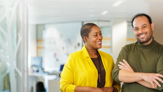 Decoratieve foto van een mannelijke en vrouwelijke collega van de Regionale Belasting groep, welke direct in de camera kijken.