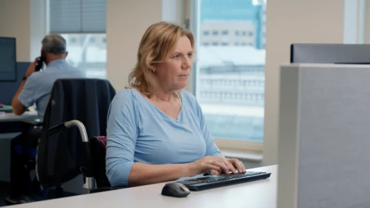 Decoratieve foto van een vrouwelijke collega in rolstoel van de Regionale Belasting groep, welke bezig is op haar computer